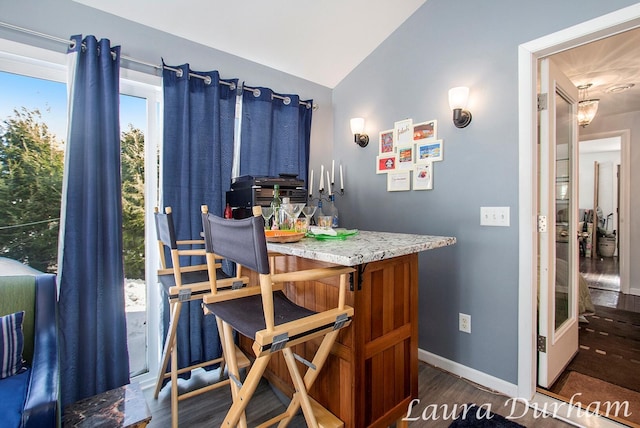 dining room featuring vaulted ceiling, dark hardwood / wood-style floors, and bar area