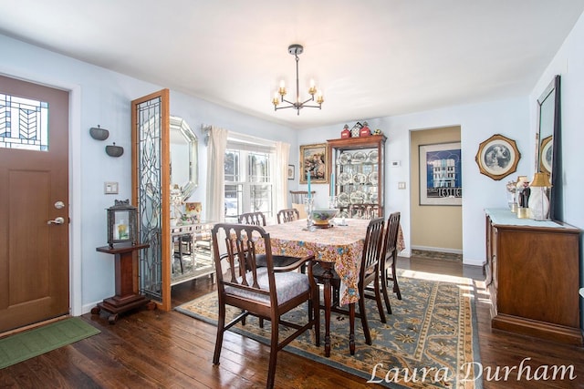 dining space with dark hardwood / wood-style floors and a notable chandelier