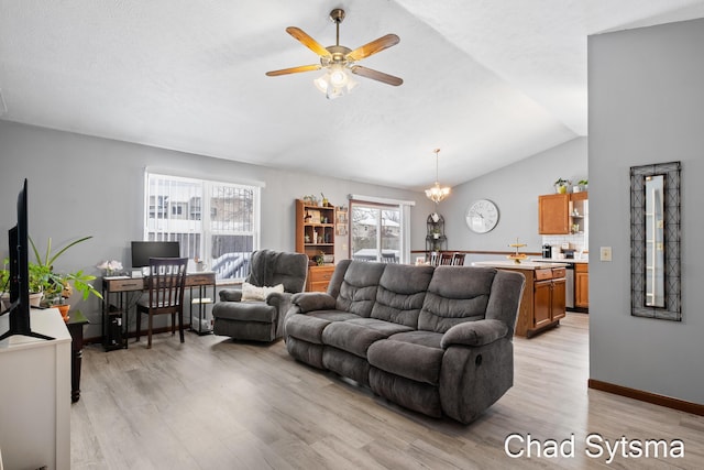 living room featuring ceiling fan with notable chandelier, lofted ceiling, and light hardwood / wood-style floors