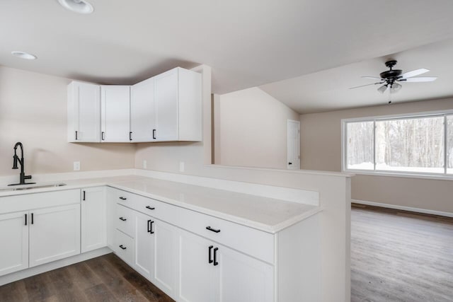 kitchen with white cabinetry, kitchen peninsula, ceiling fan, dark hardwood / wood-style flooring, and sink