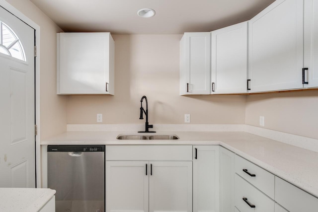 kitchen with light stone countertops, white cabinetry, stainless steel dishwasher, and sink