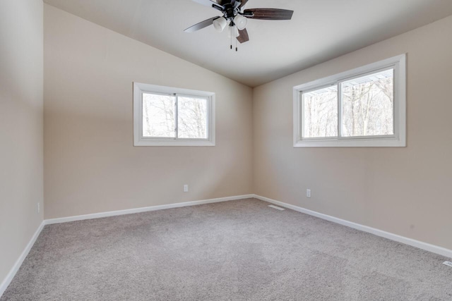 spare room featuring ceiling fan, plenty of natural light, light colored carpet, and vaulted ceiling