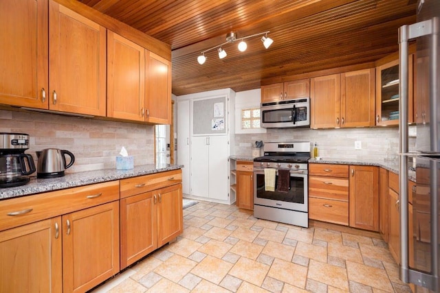 kitchen featuring appliances with stainless steel finishes, light stone countertops, wooden ceiling, rail lighting, and decorative backsplash