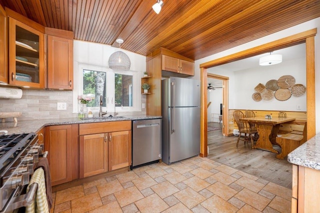 kitchen with light stone countertops, stainless steel appliances, sink, hanging light fixtures, and wooden ceiling