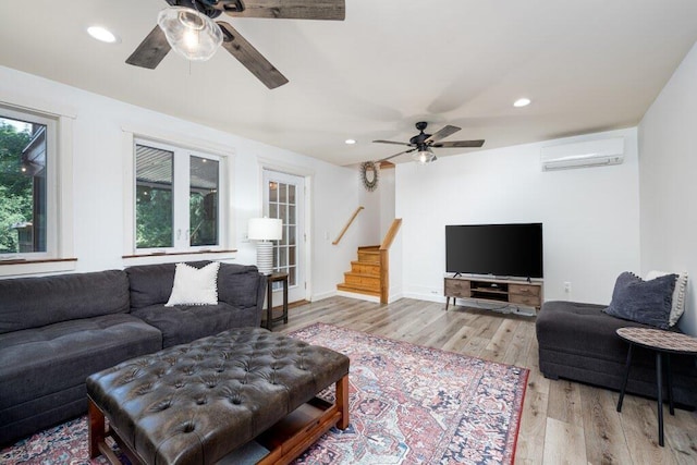 living room featuring ceiling fan, a wall mounted AC, and light hardwood / wood-style floors