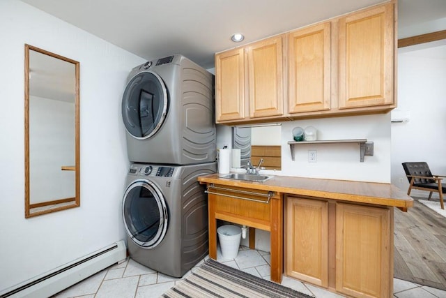 laundry room featuring a baseboard heating unit, sink, light tile patterned floors, cabinets, and stacked washer / dryer