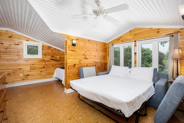 bedroom with ceiling fan, wood walls, and lofted ceiling