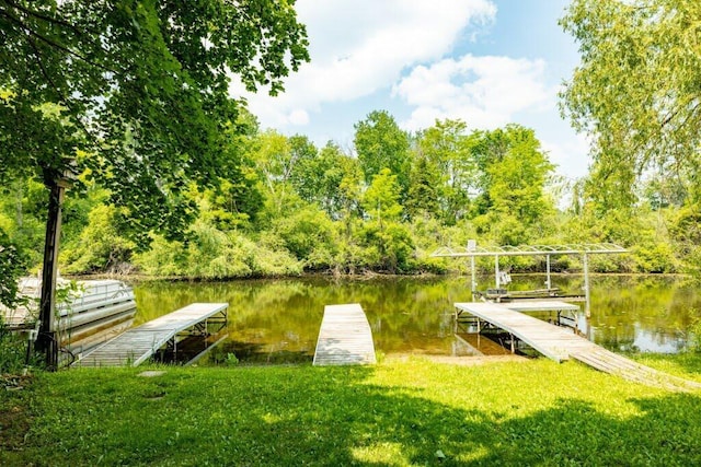 view of dock featuring a lawn and a water view