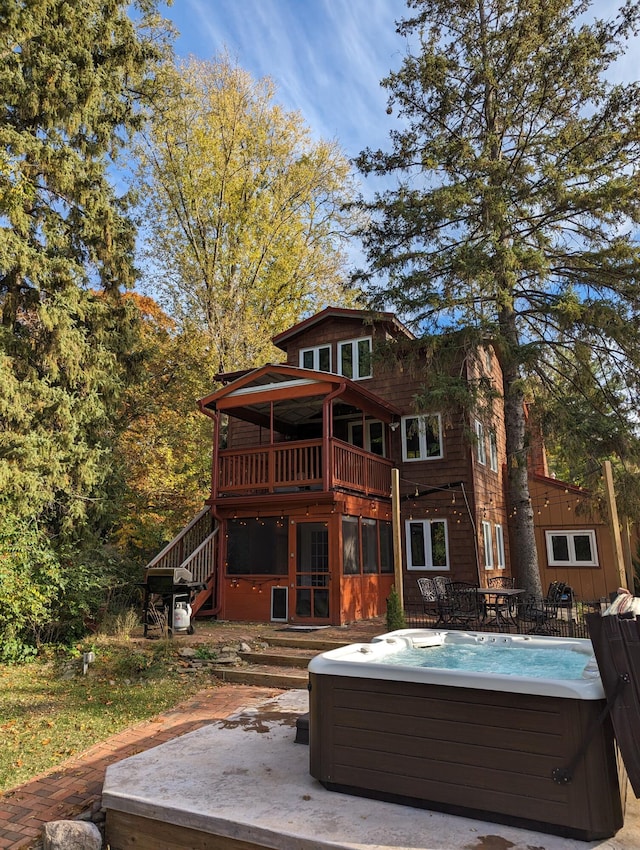 rear view of house with a deck and a hot tub