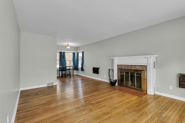 unfurnished living room with heating unit, a fireplace, and hardwood / wood-style flooring