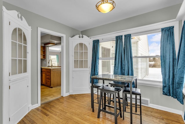 dining area featuring light wood-type flooring, plenty of natural light, and sink