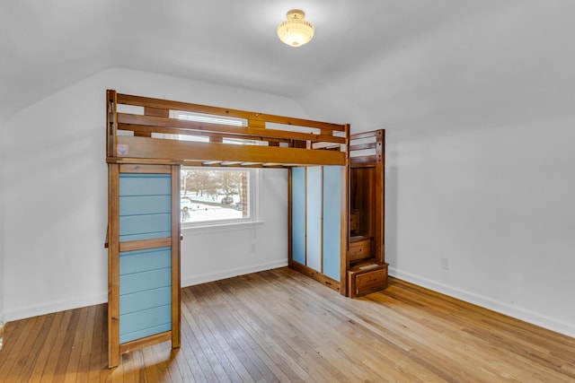 unfurnished bedroom with lofted ceiling and light hardwood / wood-style flooring