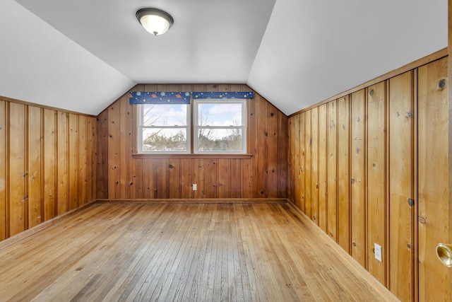 additional living space featuring hardwood / wood-style flooring, wood walls, and vaulted ceiling