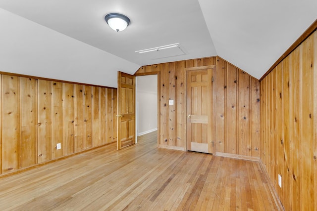 bonus room with hardwood / wood-style flooring, wooden walls, and vaulted ceiling