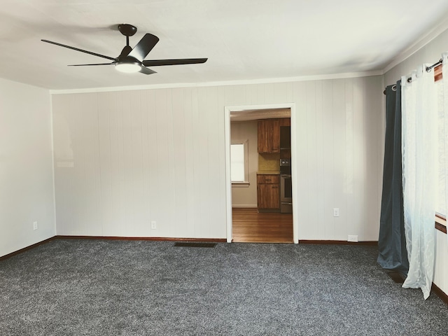 spare room featuring ceiling fan and dark carpet