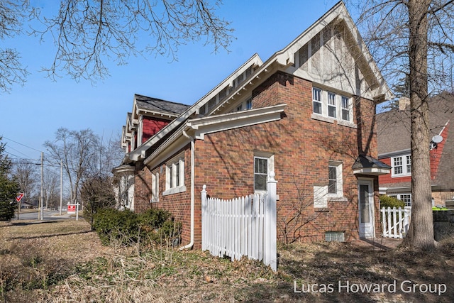 view of property exterior featuring brick siding and fence