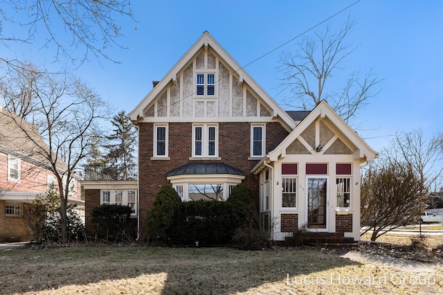 tudor home with a front lawn and brick siding