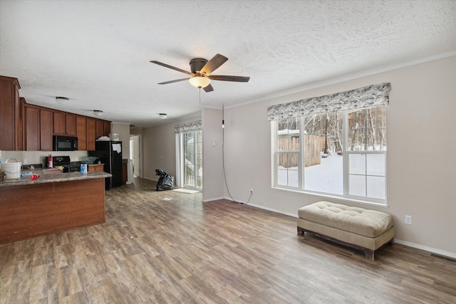 kitchen with ceiling fan, black appliances, hardwood / wood-style flooring, light stone countertops, and a textured ceiling