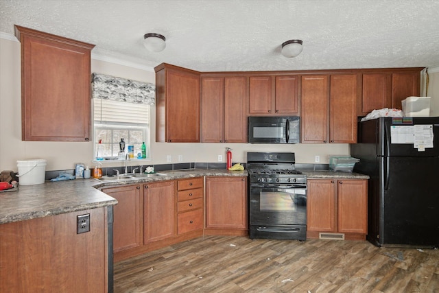 kitchen featuring dark hardwood / wood-style floors, a textured ceiling, ornamental molding, black appliances, and sink