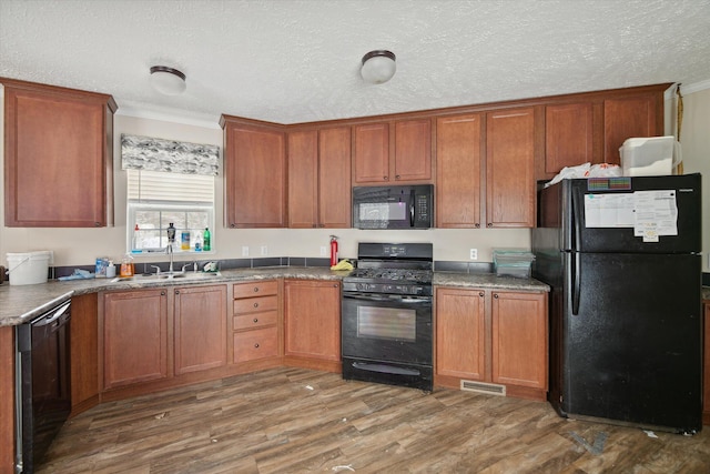 kitchen with a textured ceiling, dark hardwood / wood-style flooring, sink, and black appliances