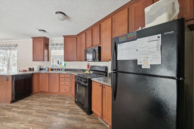 kitchen with a textured ceiling, black appliances, sink, ornamental molding, and light hardwood / wood-style flooring