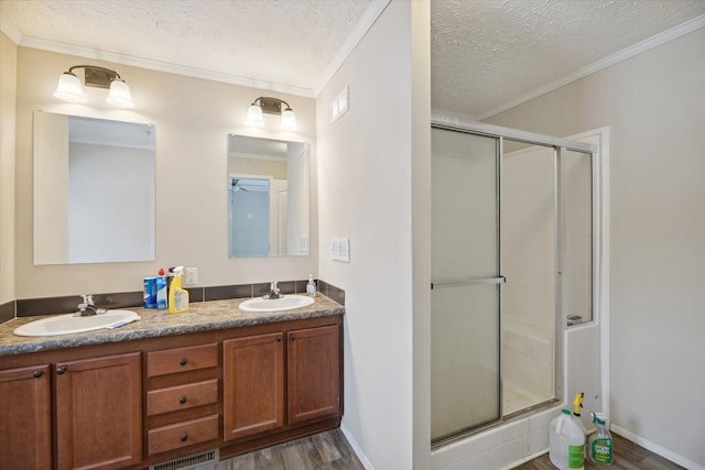 bathroom with a textured ceiling, ornamental molding, hardwood / wood-style flooring, and walk in shower