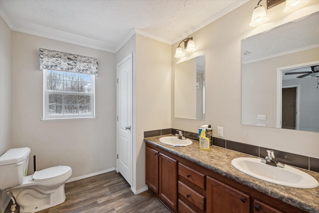 bathroom featuring toilet, vanity, hardwood / wood-style floors, crown molding, and a textured ceiling