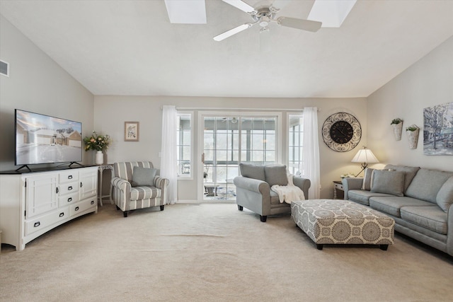 living room featuring ceiling fan, lofted ceiling with skylight, and light carpet