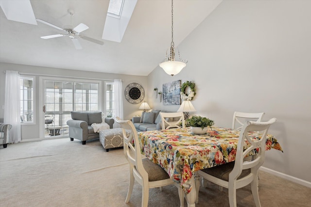 dining room with ceiling fan, lofted ceiling with skylight, and carpet flooring