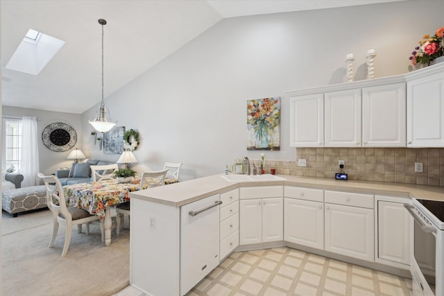 kitchen featuring white cabinetry, vaulted ceiling with skylight, sink, pendant lighting, and backsplash