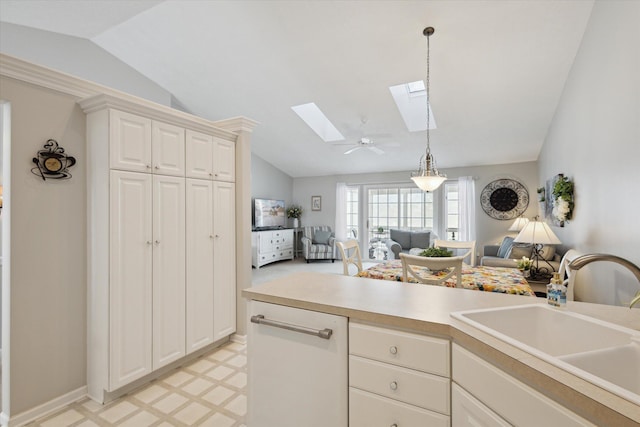 kitchen featuring sink, decorative light fixtures, white cabinets, and vaulted ceiling with skylight