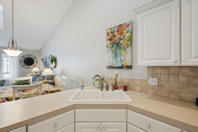 kitchen featuring sink, decorative light fixtures, white cabinetry, decorative backsplash, and lofted ceiling