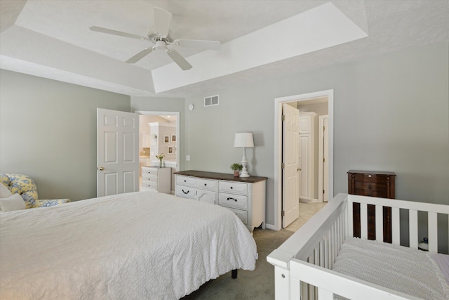 carpeted bedroom featuring ceiling fan and a raised ceiling