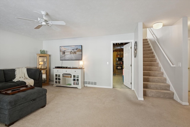 carpeted living room with ceiling fan and a textured ceiling