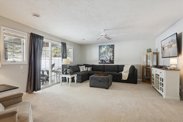 living room with ceiling fan, light colored carpet, and a textured ceiling