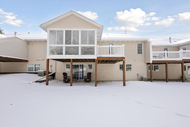 snow covered property featuring central air condition unit and a sunroom