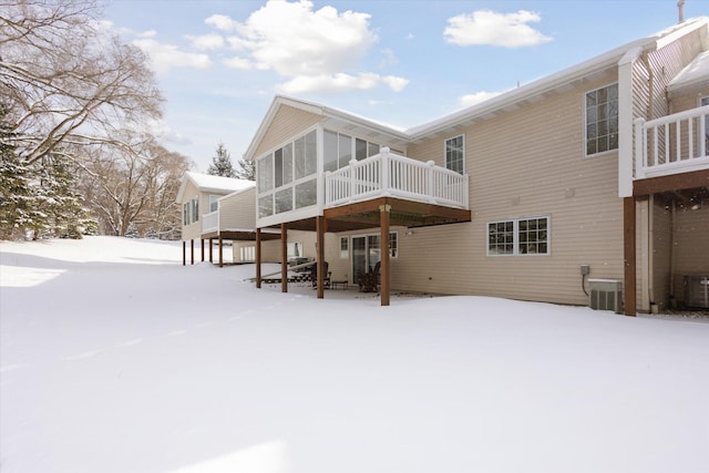 snow covered property featuring cooling unit, a deck, and a sunroom