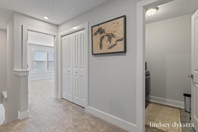 hall featuring a textured ceiling and light colored carpet