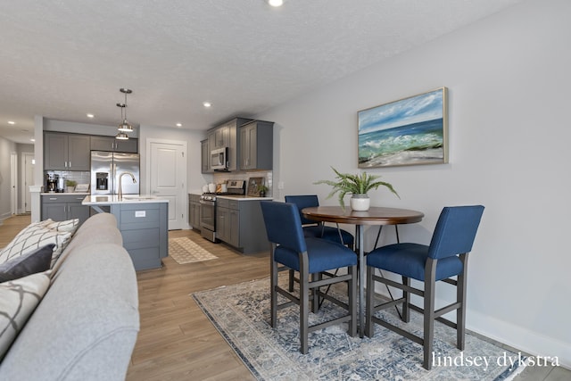 dining area with sink, a textured ceiling, and light hardwood / wood-style flooring