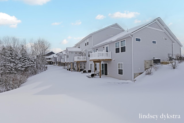 snow covered rear of property featuring central AC