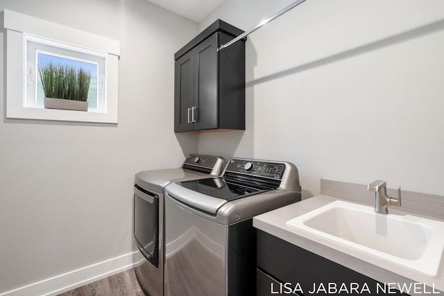 laundry area with cabinets, hardwood / wood-style flooring, sink, and washing machine and clothes dryer