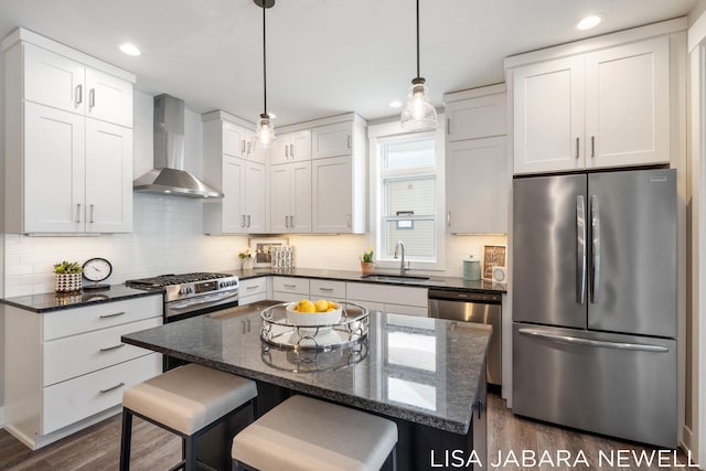 kitchen featuring sink, white cabinets, a center island, stainless steel appliances, and wall chimney range hood