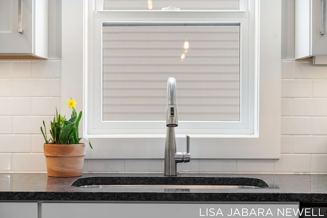 interior details featuring tasteful backsplash, sink, and white cabinets