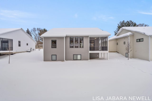 snow covered house featuring a sunroom