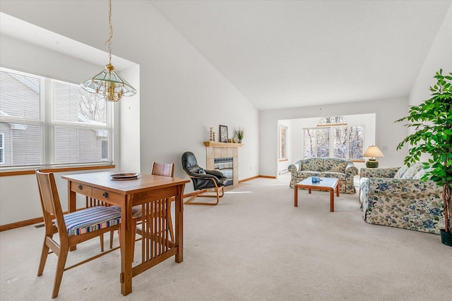 carpeted dining space with a notable chandelier, high vaulted ceiling, and a fireplace