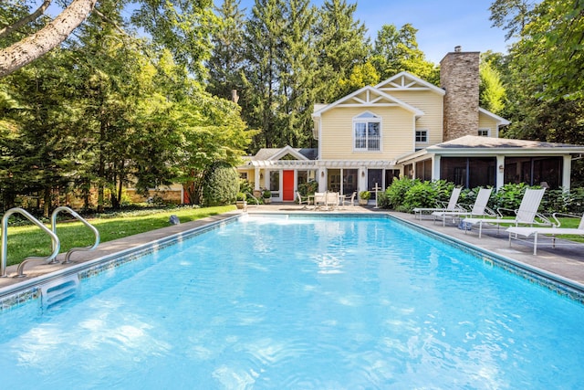 view of swimming pool featuring a sunroom and a patio area