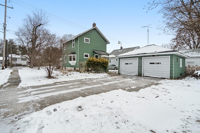 snow covered house featuring a garage