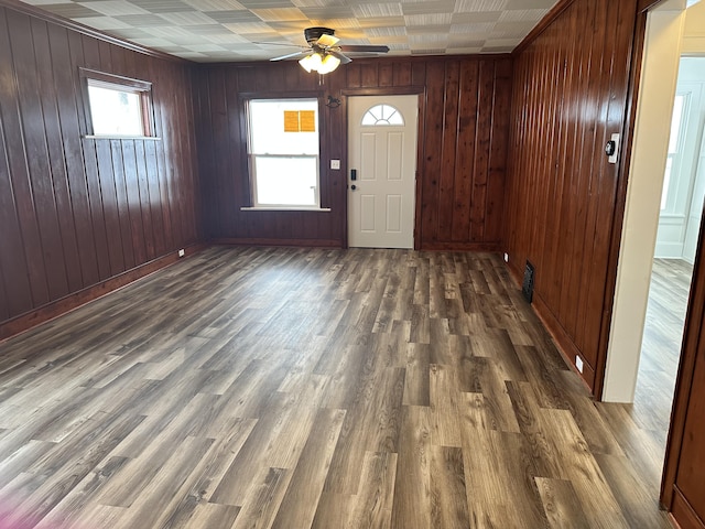 entrance foyer featuring ceiling fan, dark wood-type flooring, and wood walls