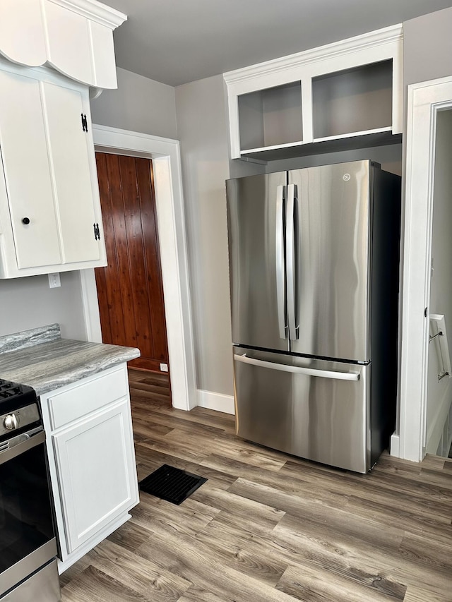 kitchen with light hardwood / wood-style floors, white cabinets, and stainless steel appliances