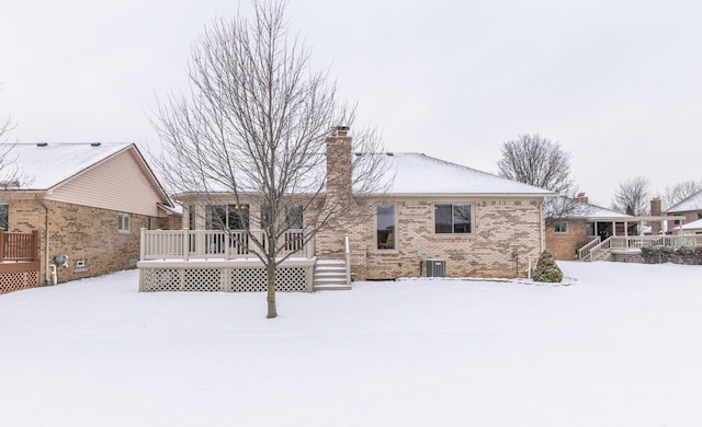 snow covered rear of property featuring a wooden deck and central AC unit